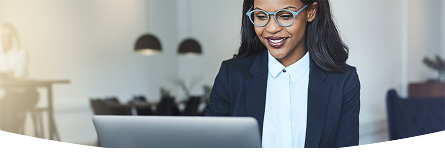 Professional woman wearing glasses smiling at a laptop