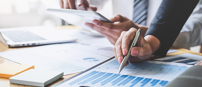 hands pointing at graphs on a paper