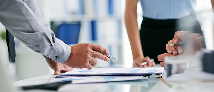 Hands on desk pointing at paper report