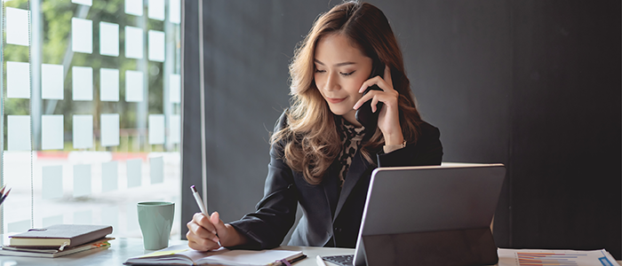 Woman on phone working on tablet