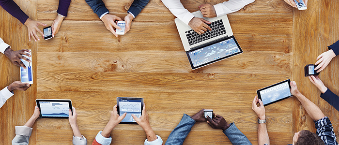 Hands holding technology items around table